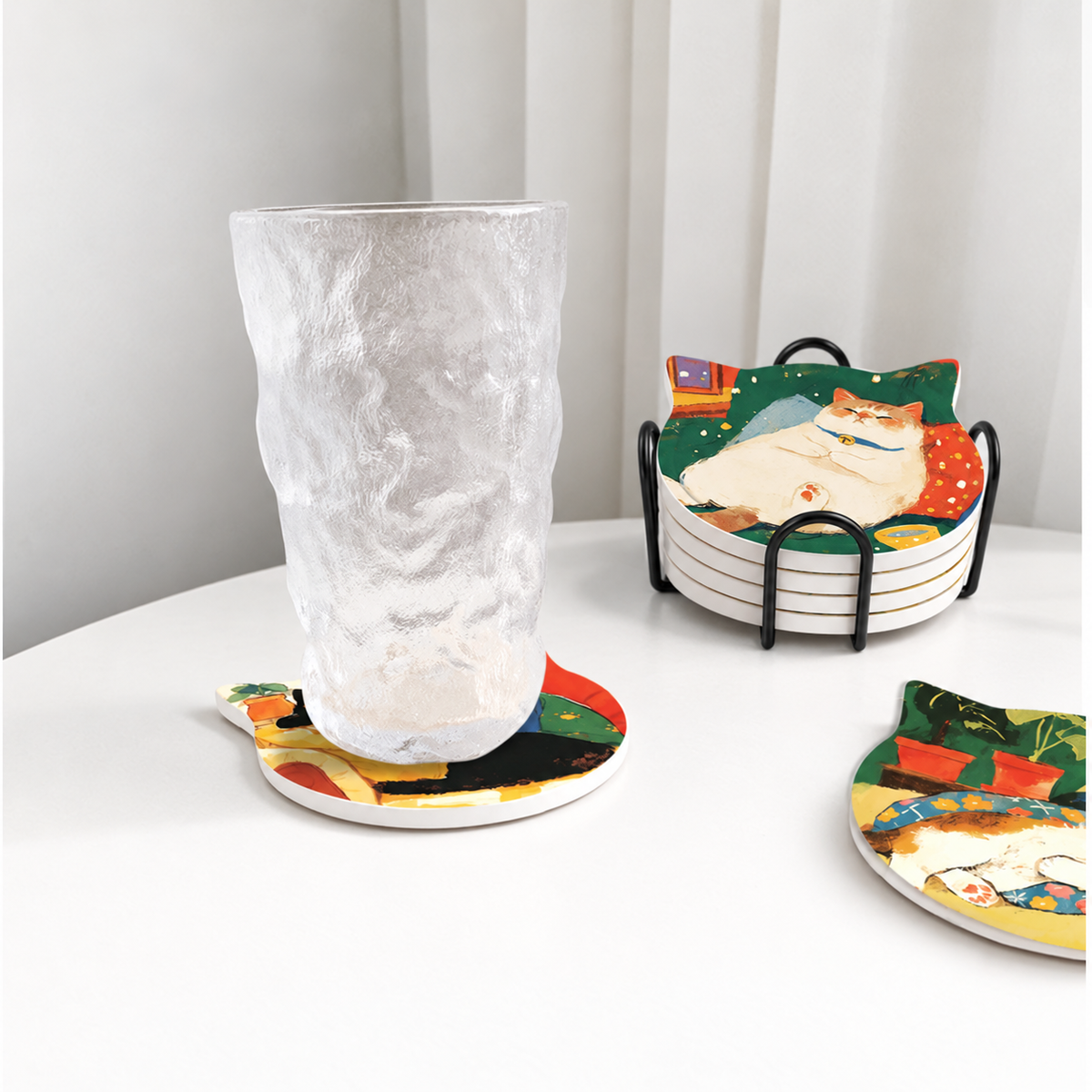 Cat-shaped ceramic coaster under a glass beside the matching set in a black iron holder.