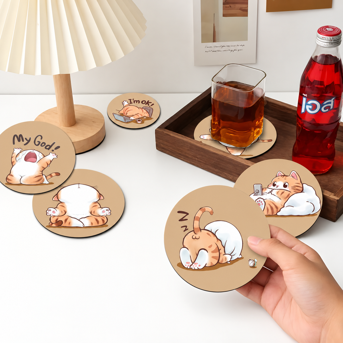 Six orange-cat coasters shown on a desk with one held in hand.