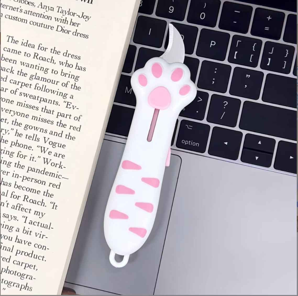 White / Pink cat paw retractable box cutter with pink paw pads and a curved stainless steel blade.